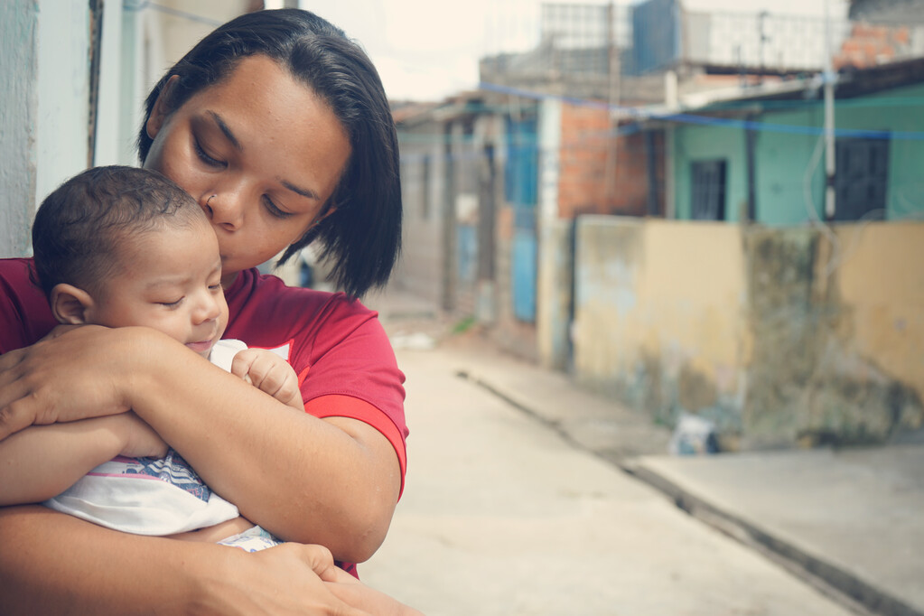 A woman kissing her baby on the head while he's on her lap.