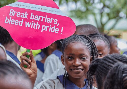 A girl standing with a pink protest sign that says 