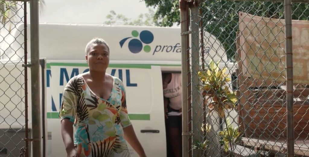 A woman stands in front of mobile health unit. 